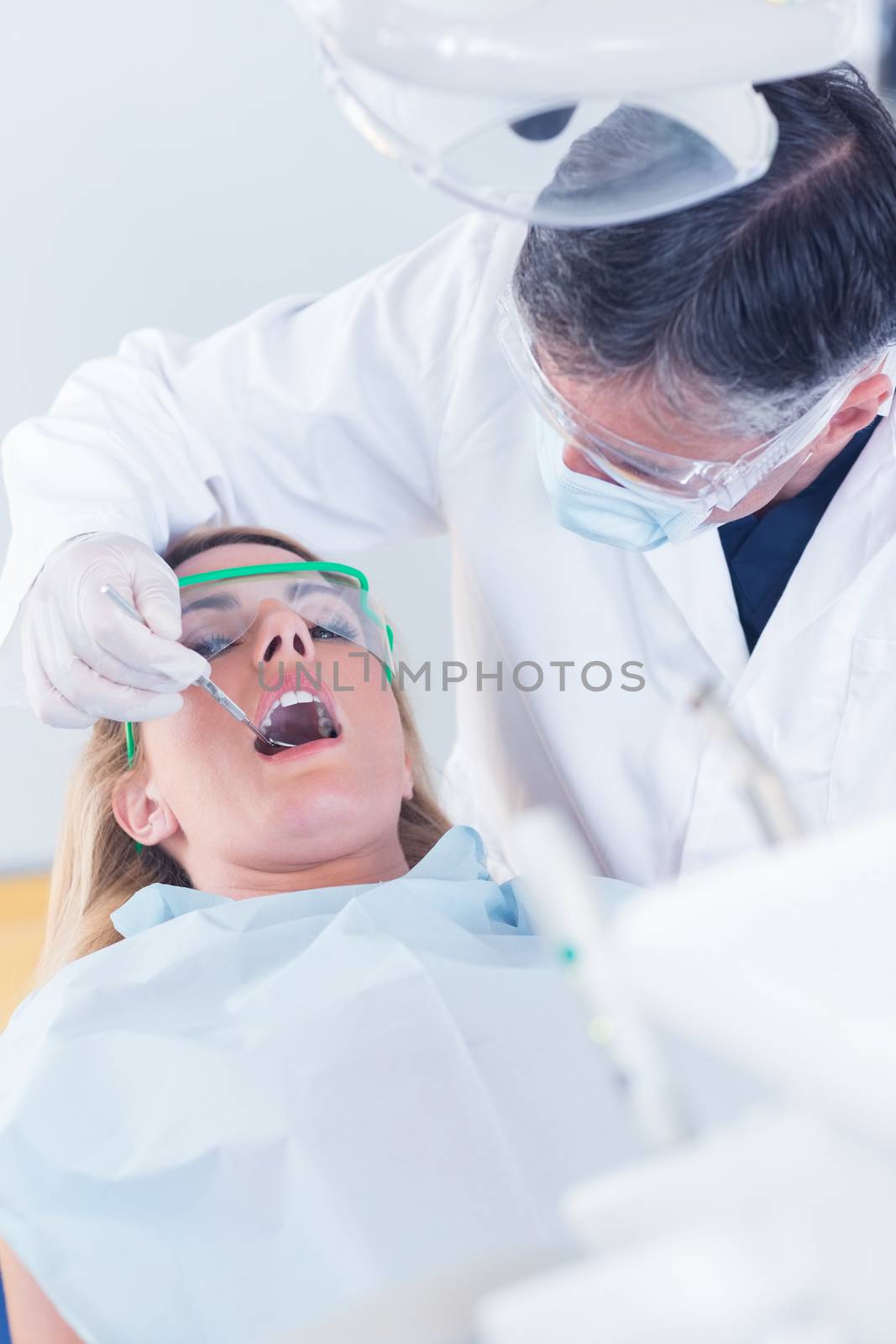 Dentist examining a patients teeth in the dentists chair at the dental clinic