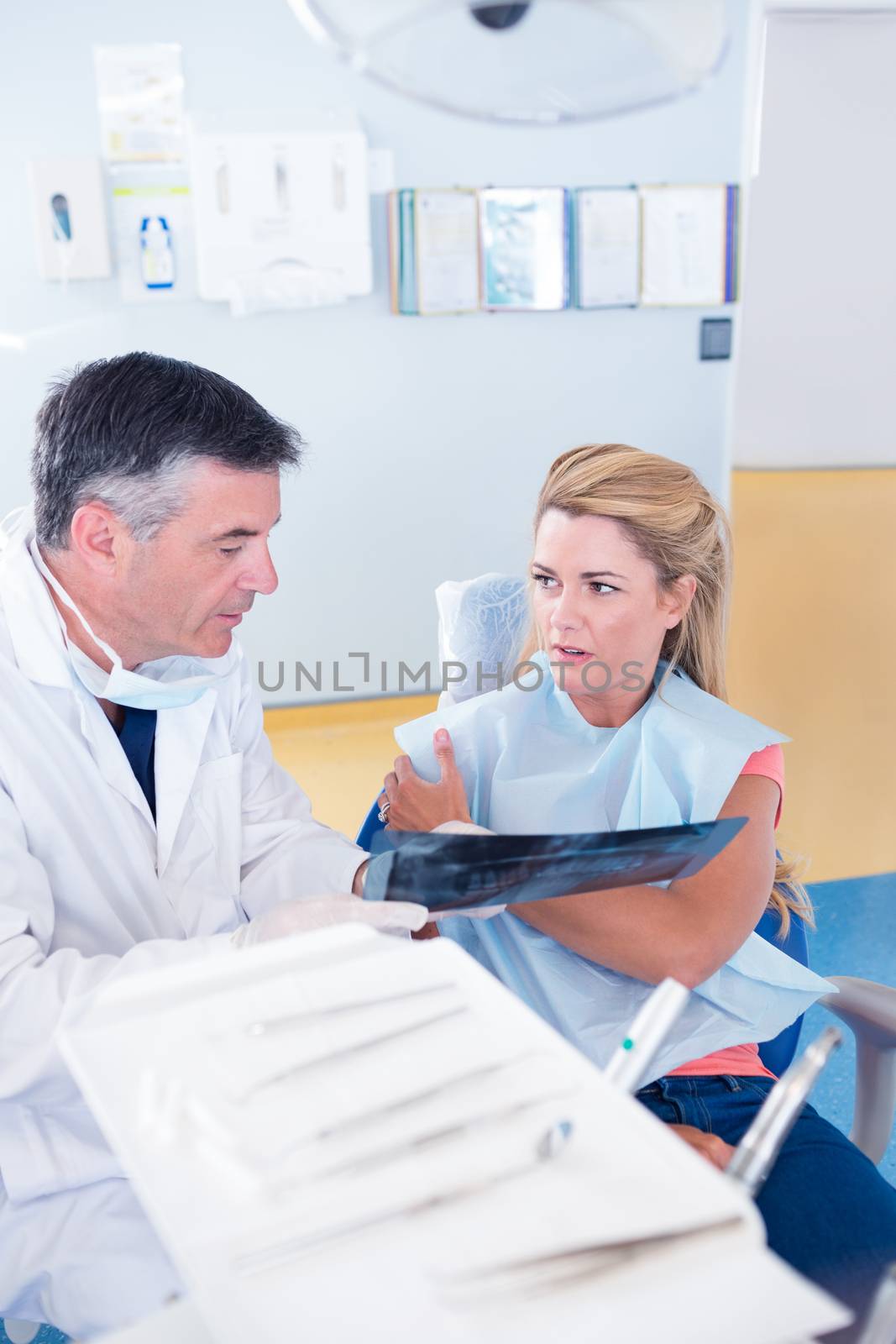 Dentist discussing x-ray with his patient by Wavebreakmedia