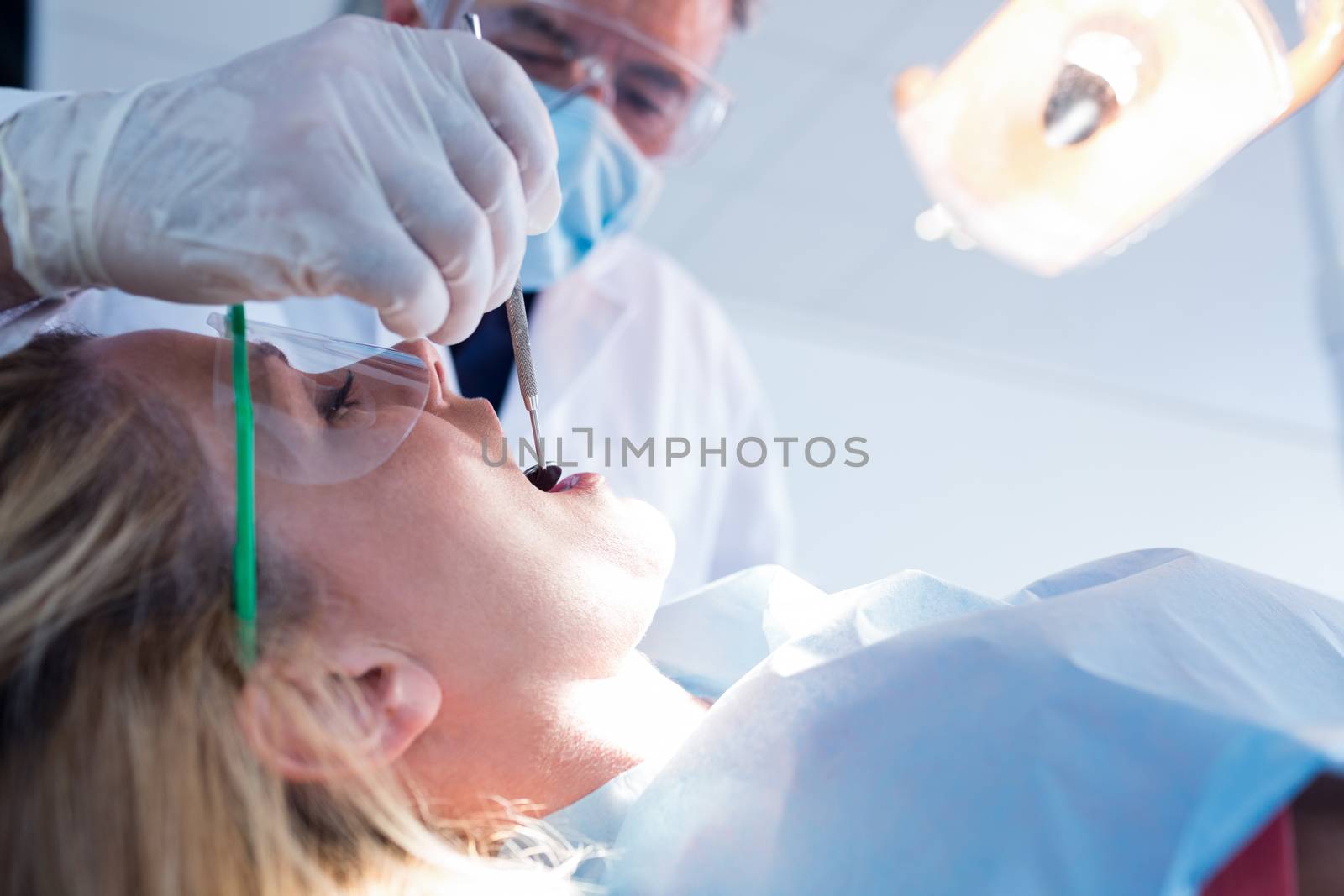 Dentist examining a patients teeth under bright light at the dental clinic