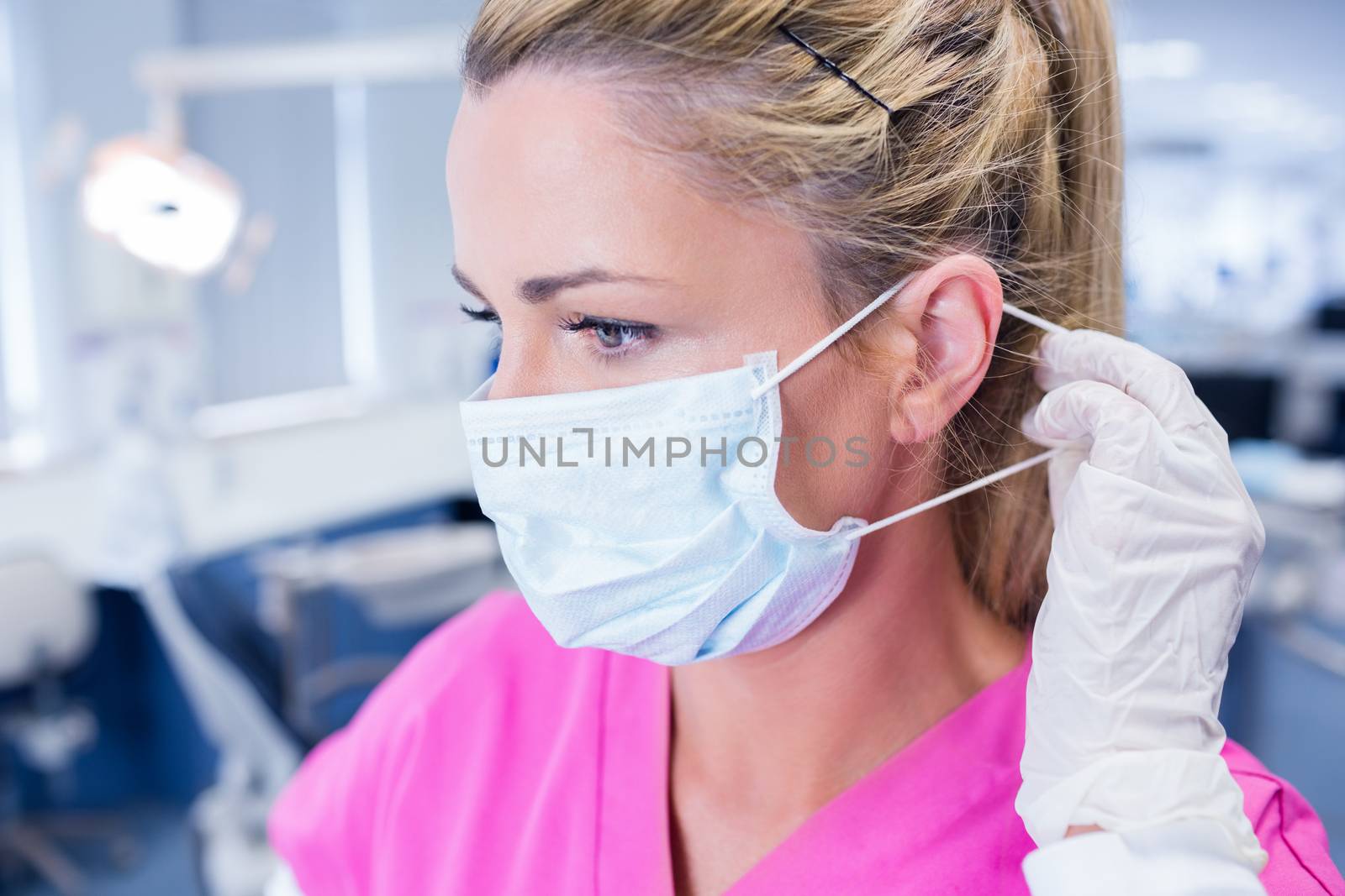 Dentist putting on her surgical mask by Wavebreakmedia