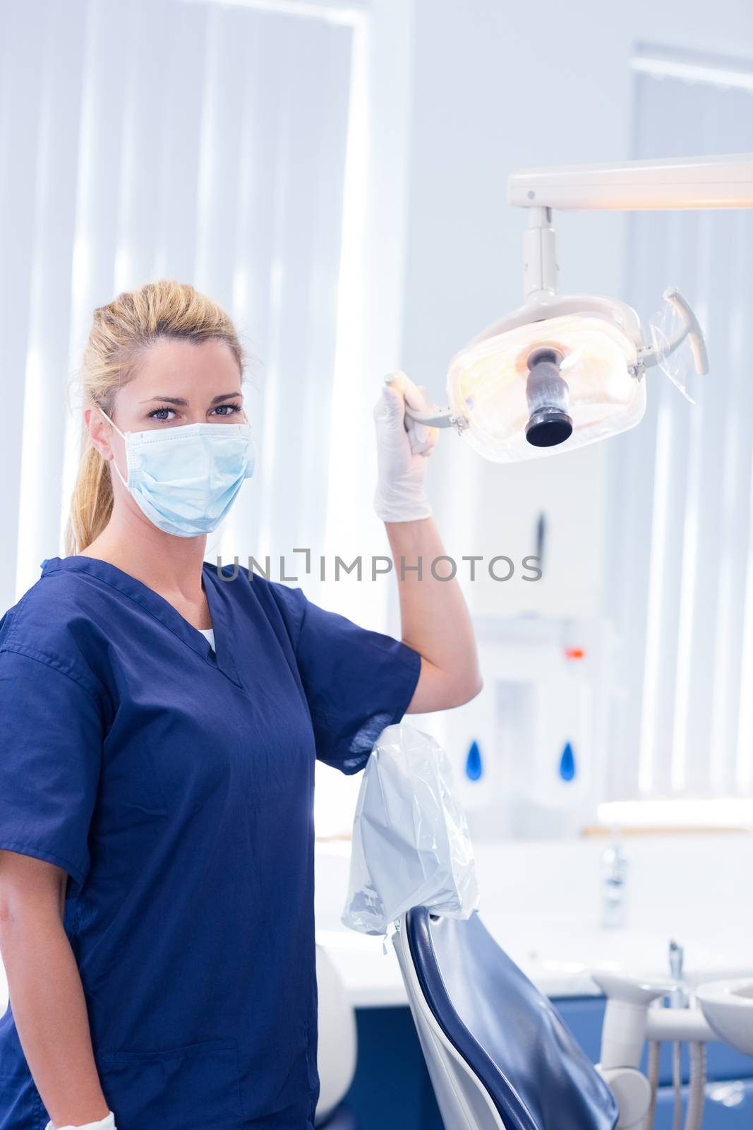 Dentist in mask holding light at the dental clinic