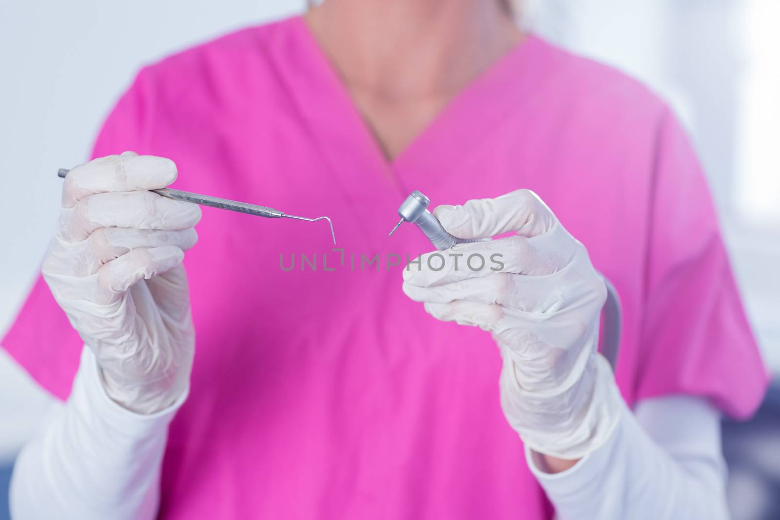 Dentist in pink scrubs holding tool at the dental clinic