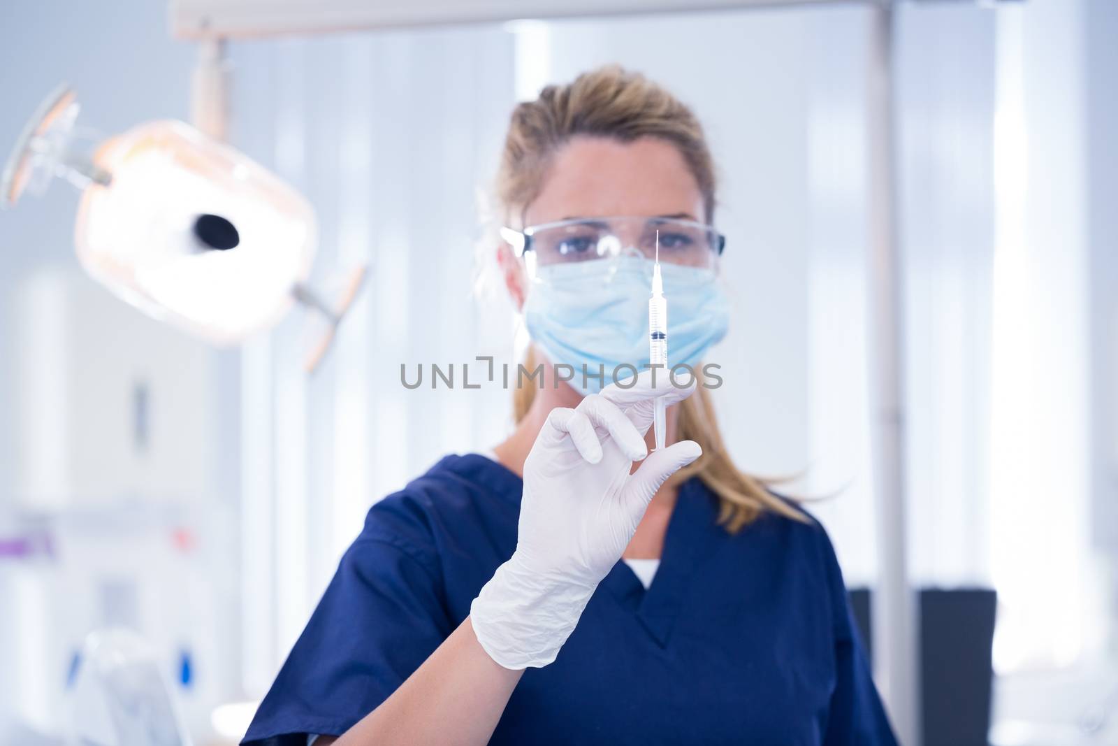 Dentist in mask and glove holding an injection at the dental clinic