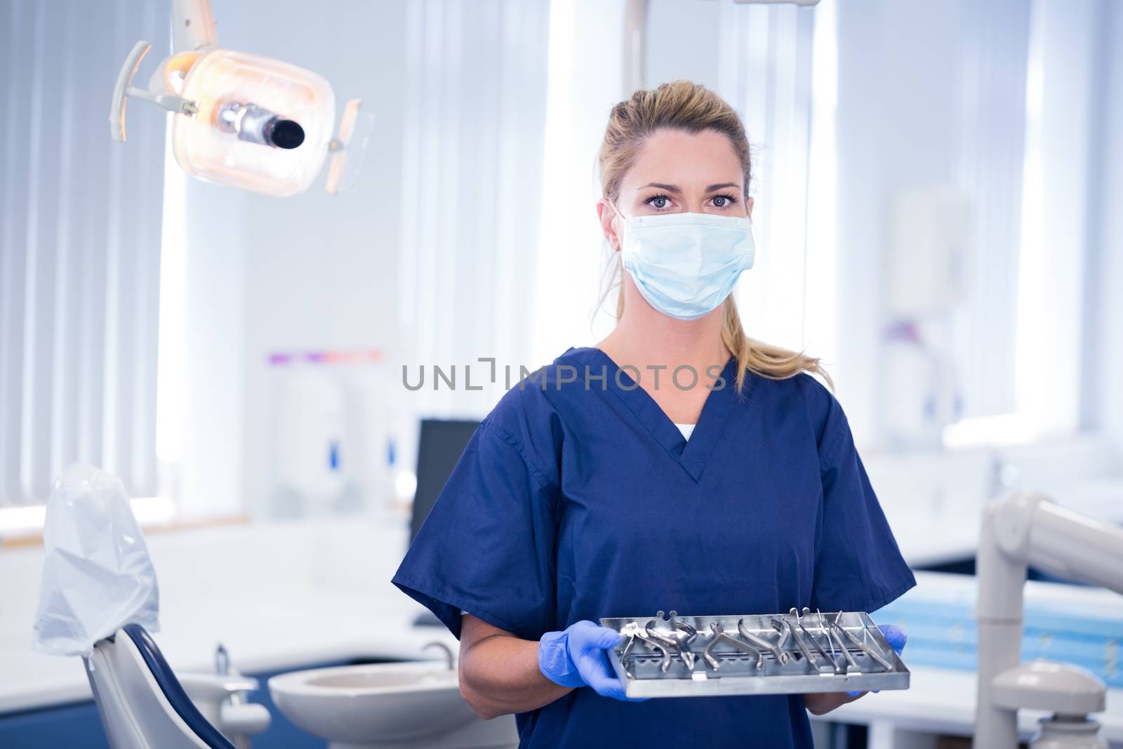 Dentist in mask holding tray of tools by Wavebreakmedia