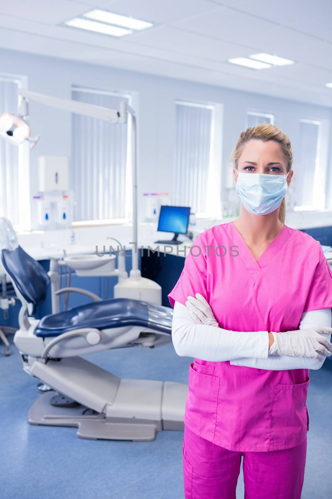 Dentist in pink scrubs standing with arms folded at the dental clinic