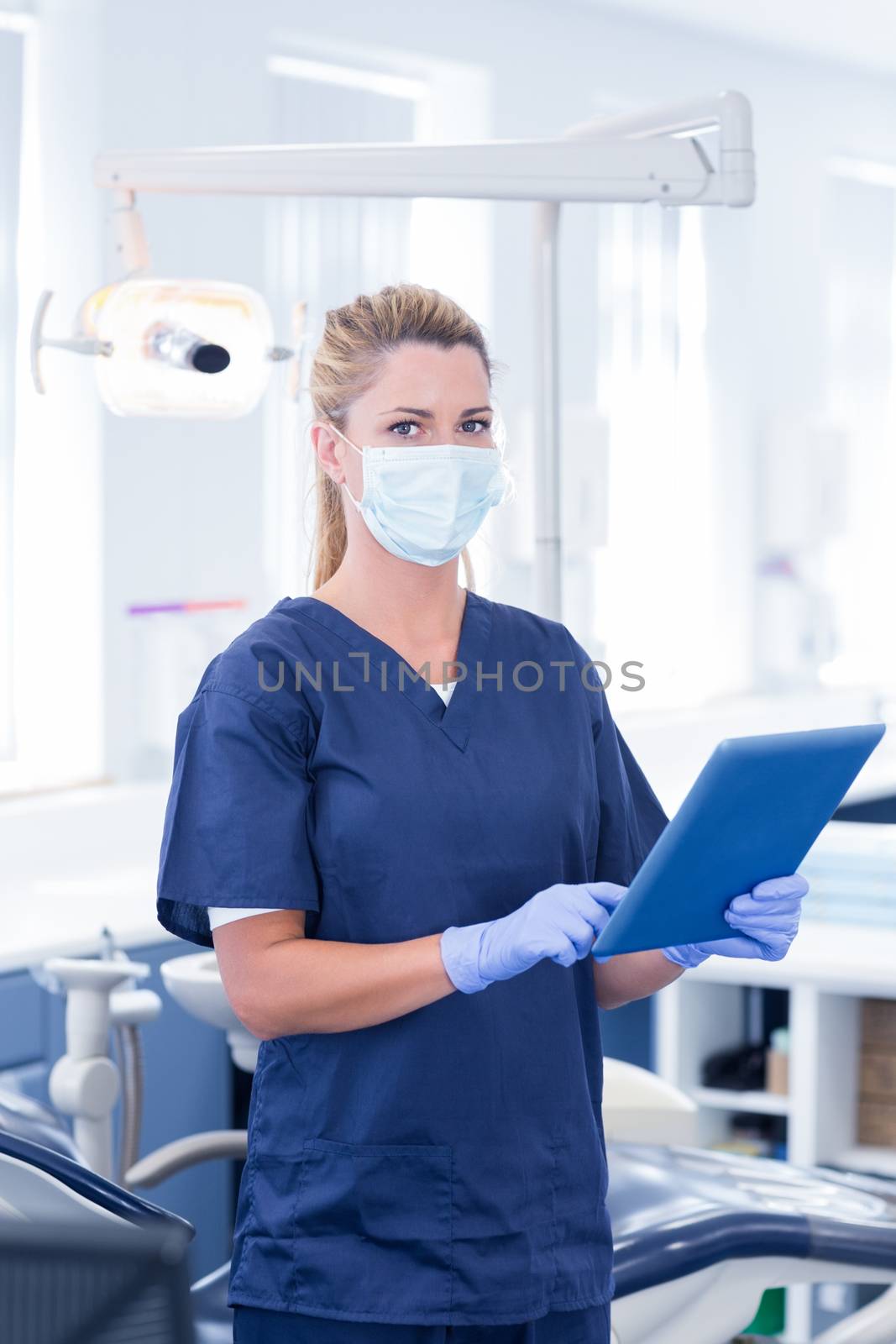 Dentist in mask using her tablet and looking at camera by Wavebreakmedia