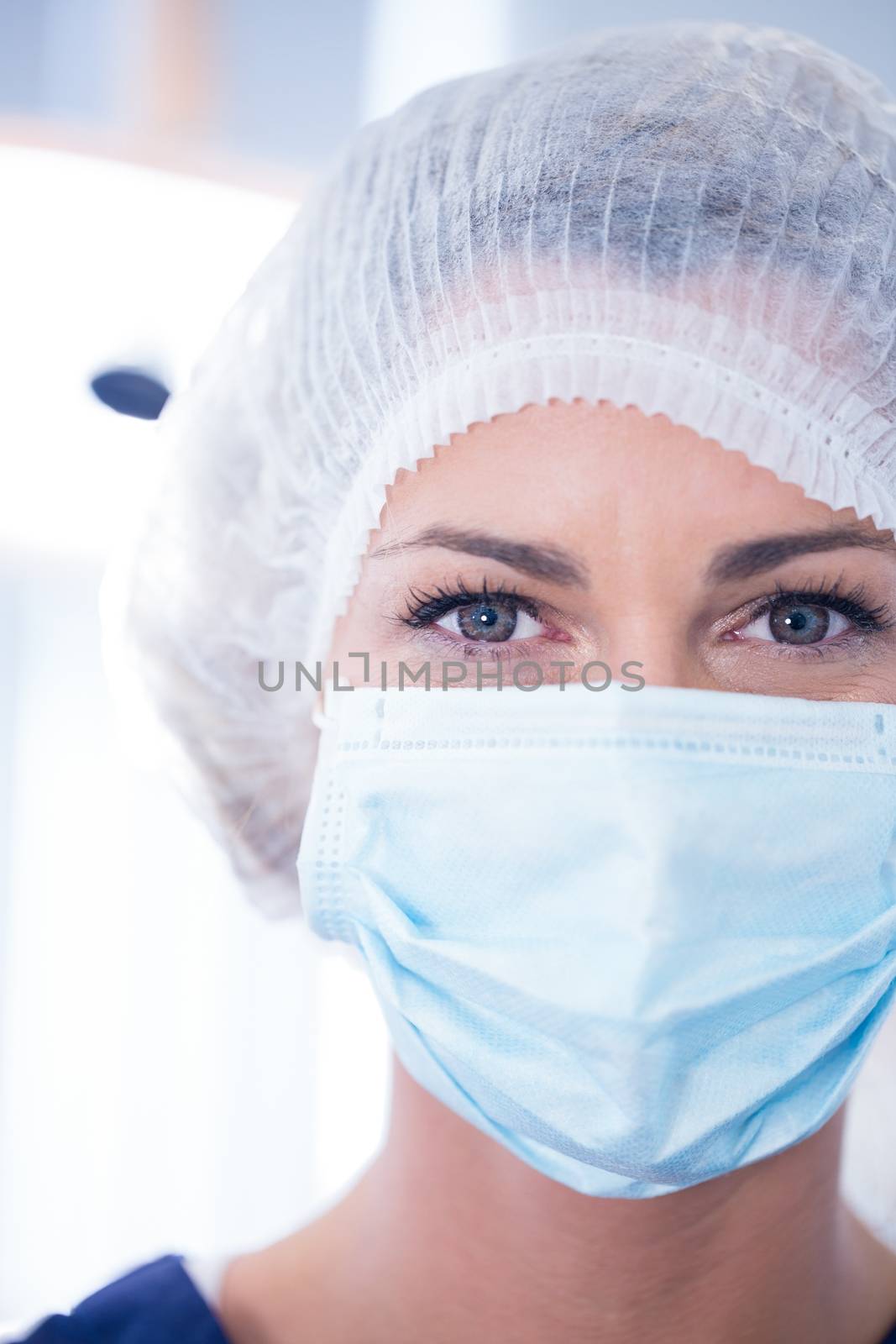 Dentist in surgical mask and cap looking at camera by Wavebreakmedia