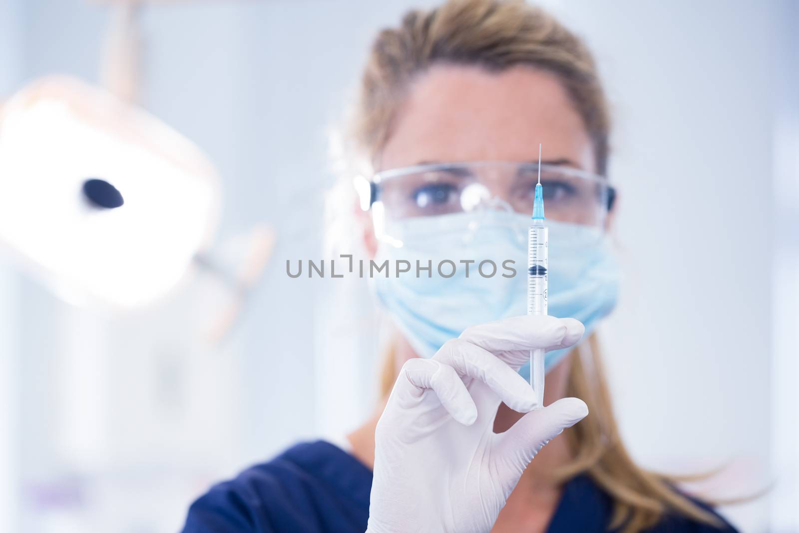 Dentist in mask and glove holding an injection by Wavebreakmedia