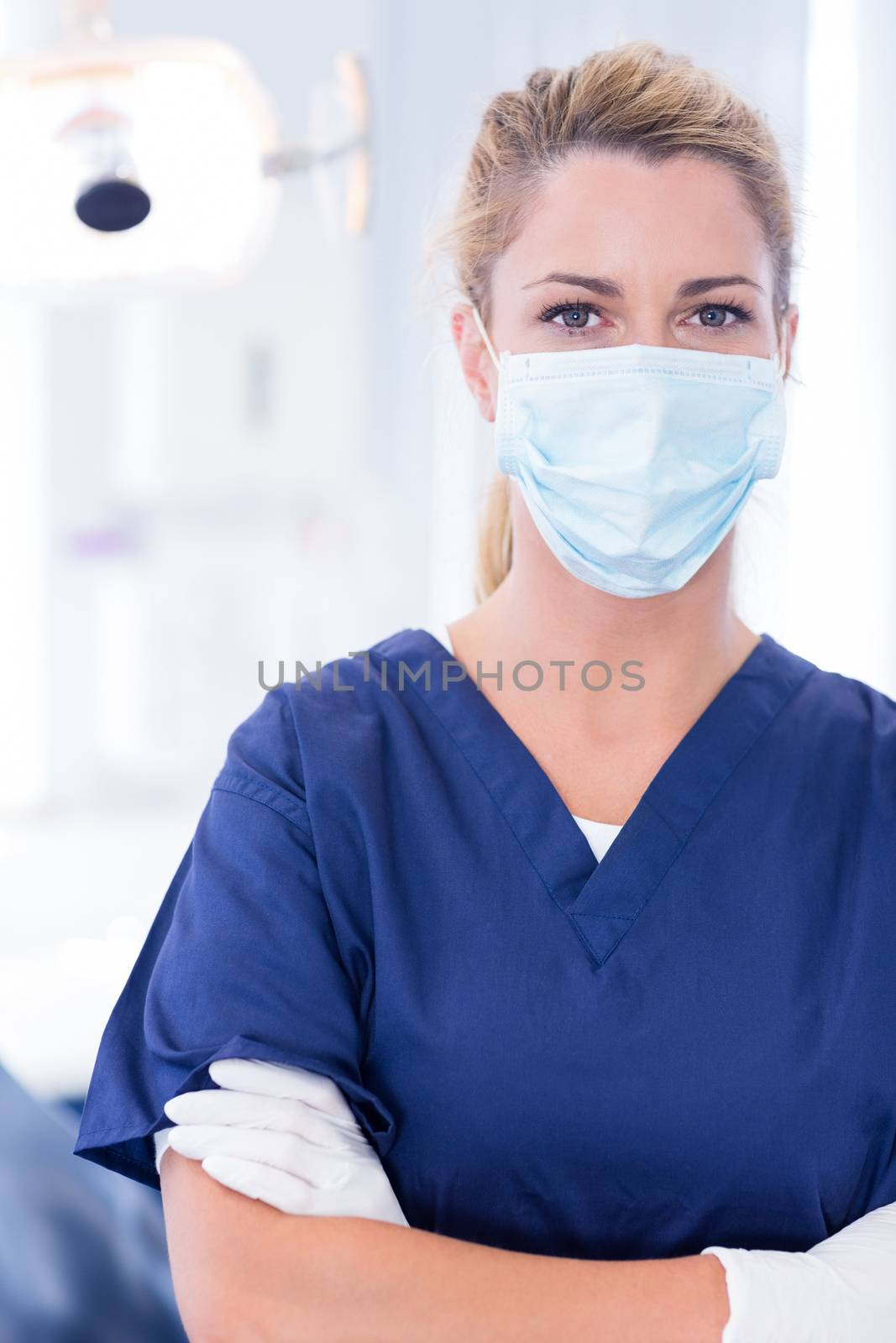 Dentist in mask looking at camera with arms crossed by Wavebreakmedia