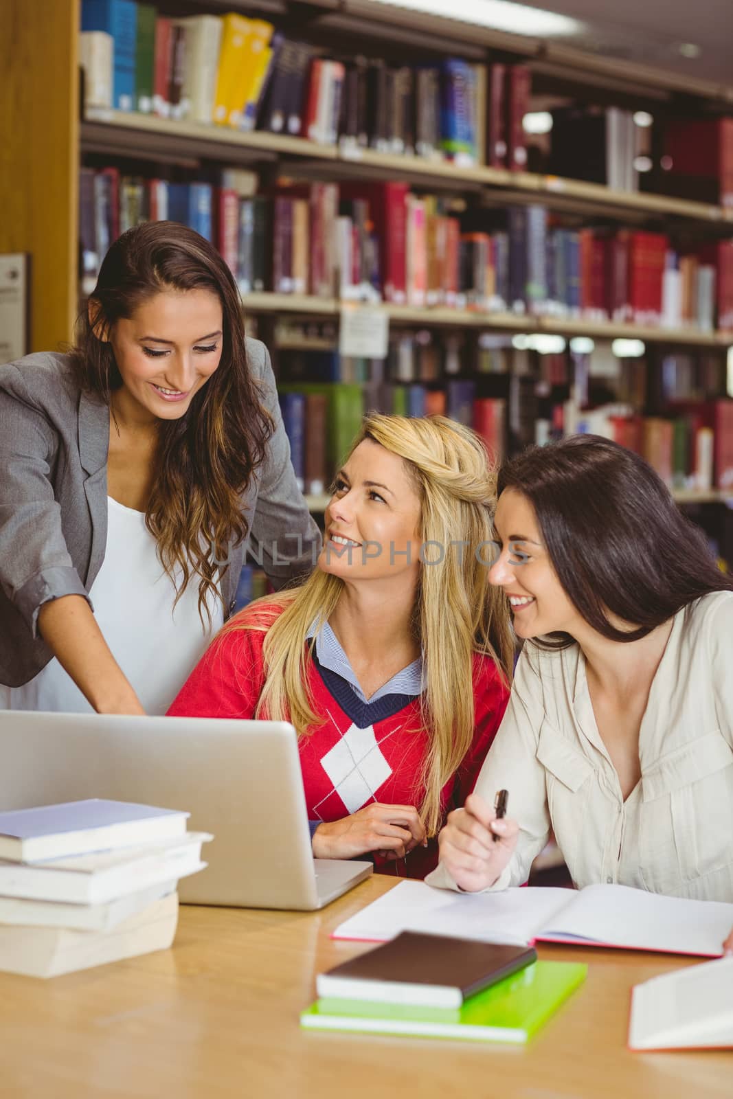 Pretty student showing her classmates something on laptop by Wavebreakmedia