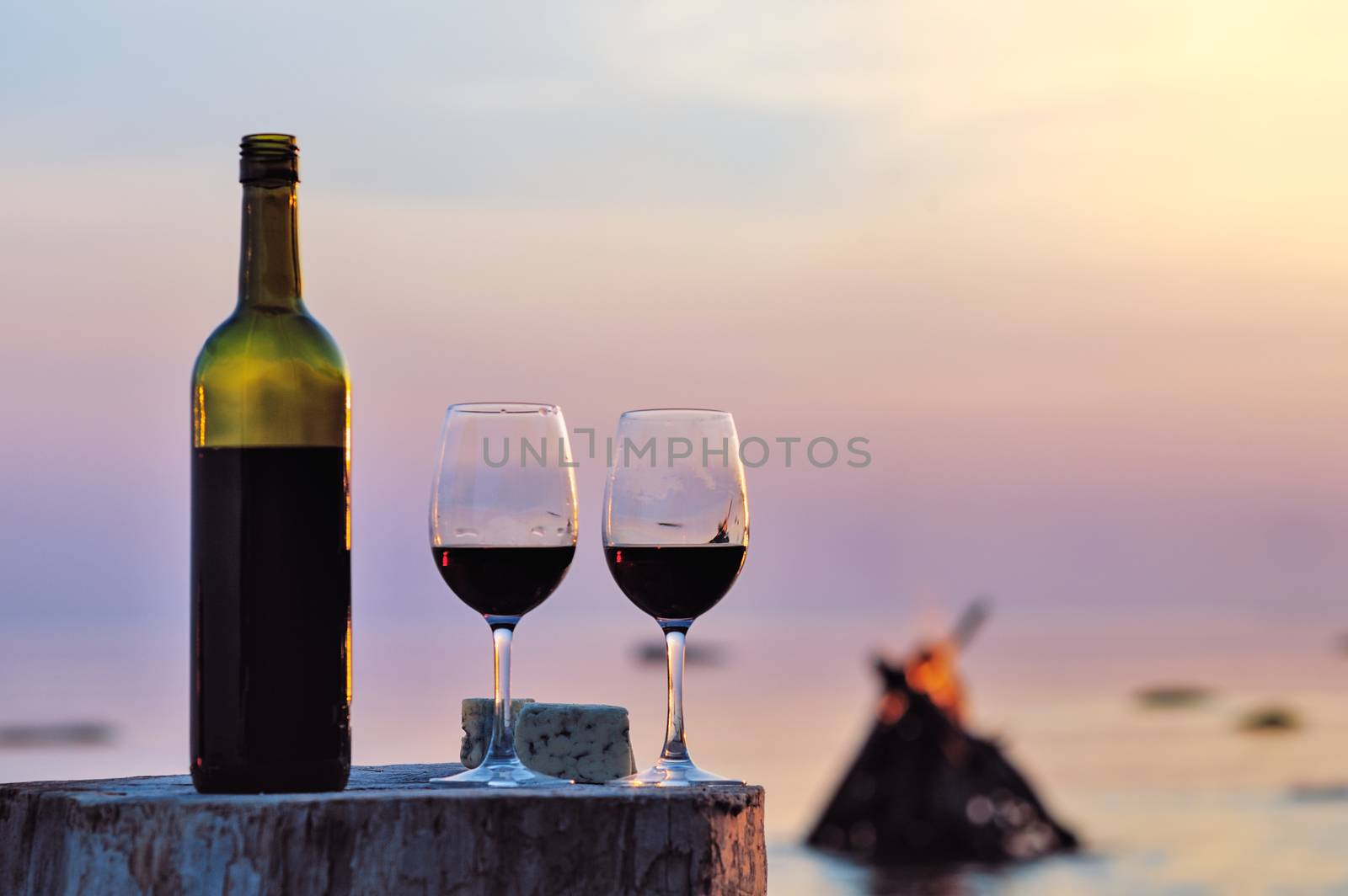 Red wine bottle and wine glasses at the sea