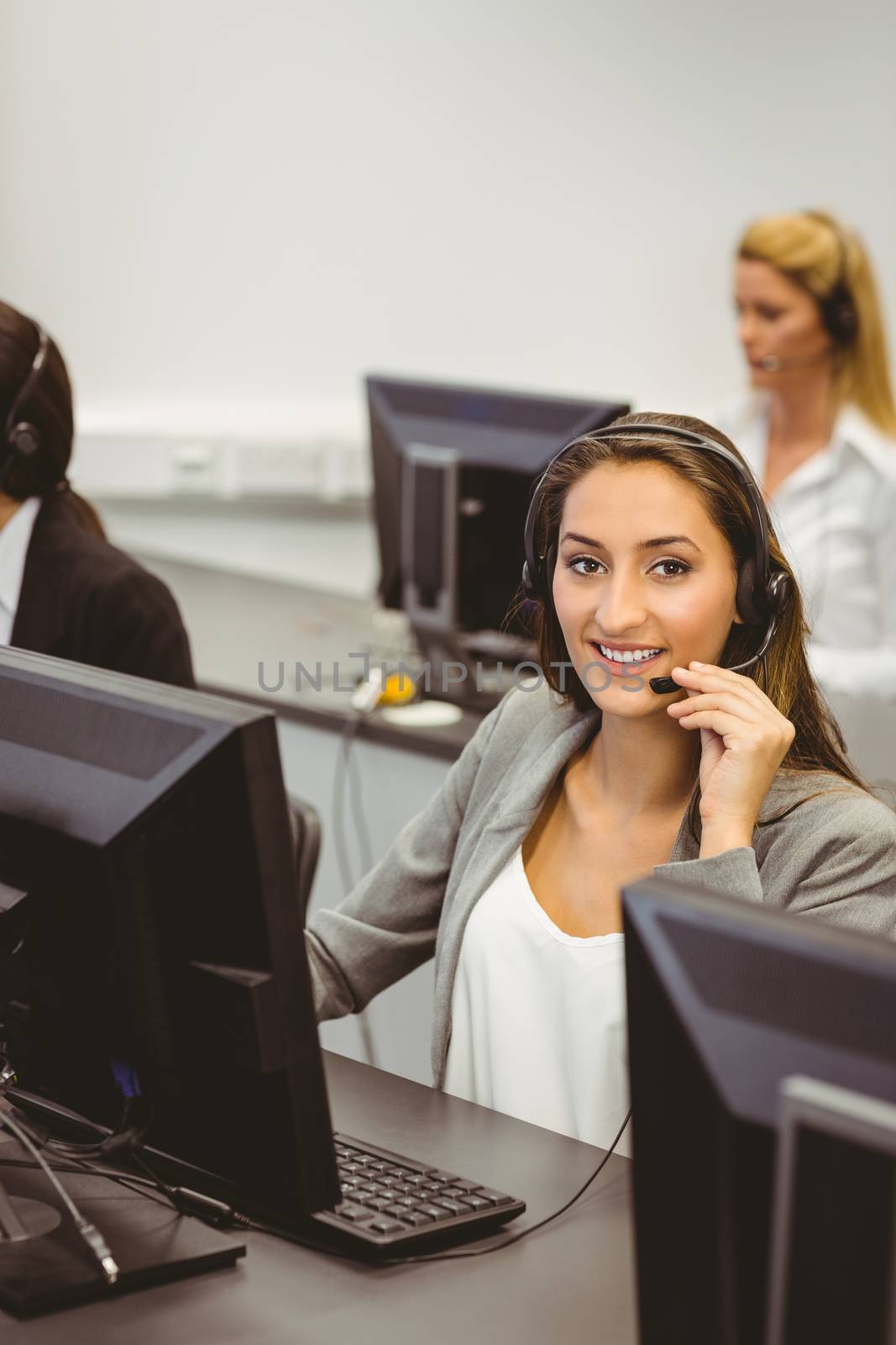 Smiling call centre agent talking on the headset by Wavebreakmedia