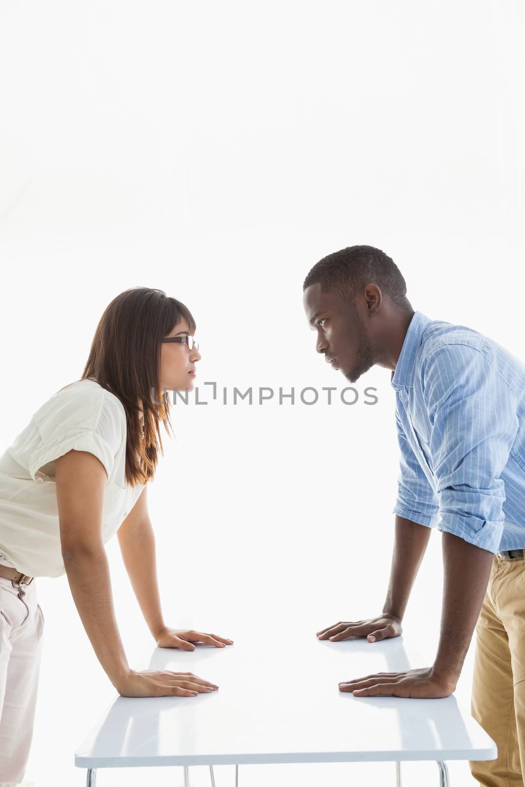Business people having a stand off at their desk on white background
