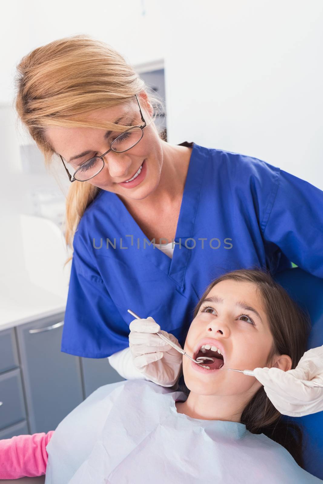 Pediatric dentist doing examination at a scared young patient by Wavebreakmedia