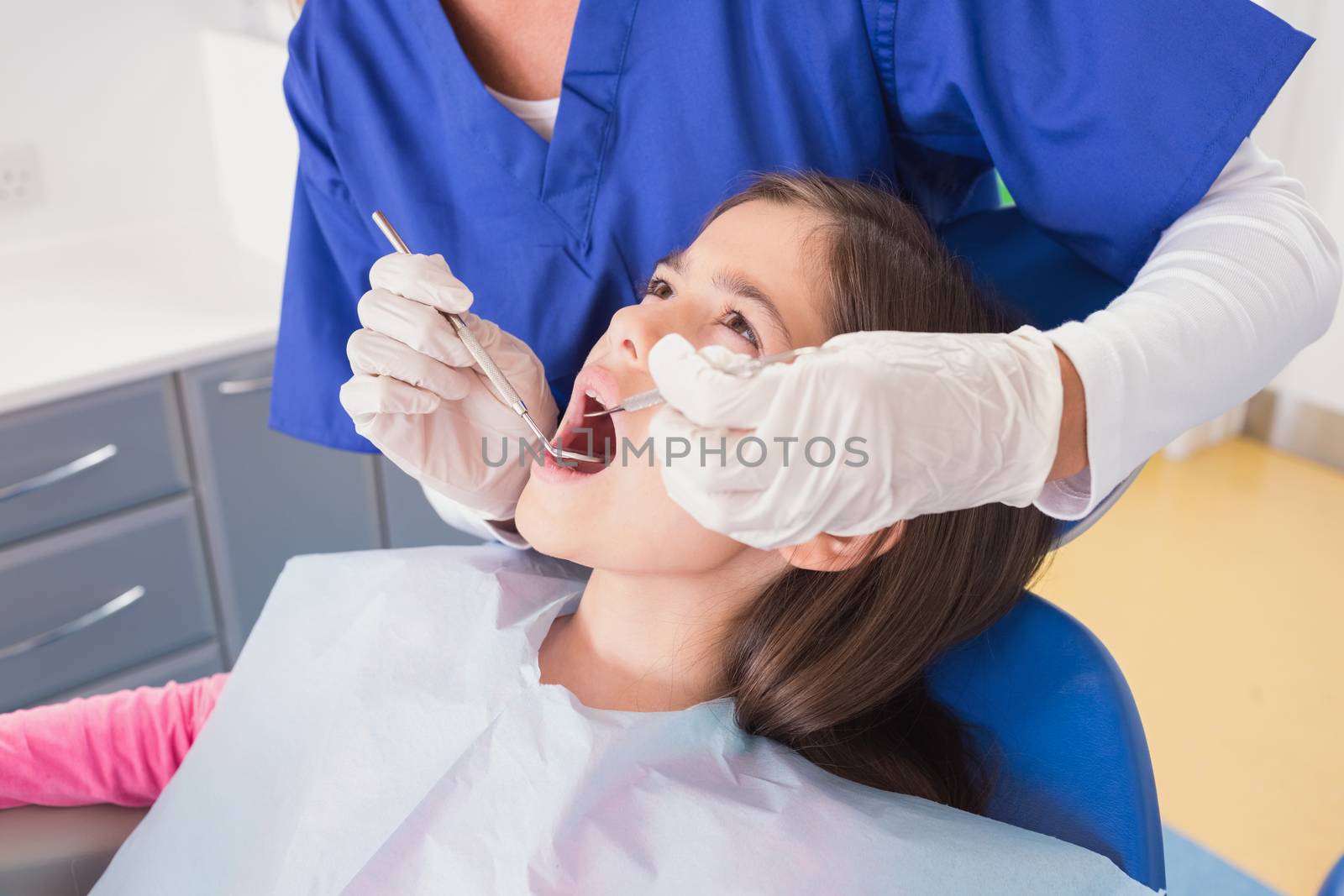 Pediatric dentist doing examination at a scared young patient in dental clinic