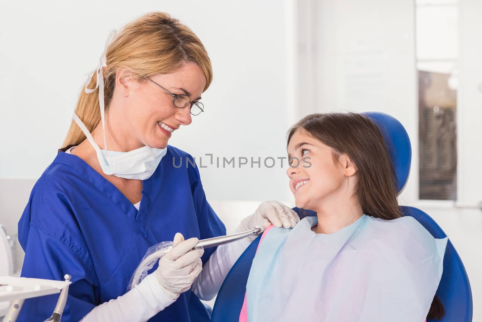 Smiling pediatric dentist reassuring her young patient in dental clinic