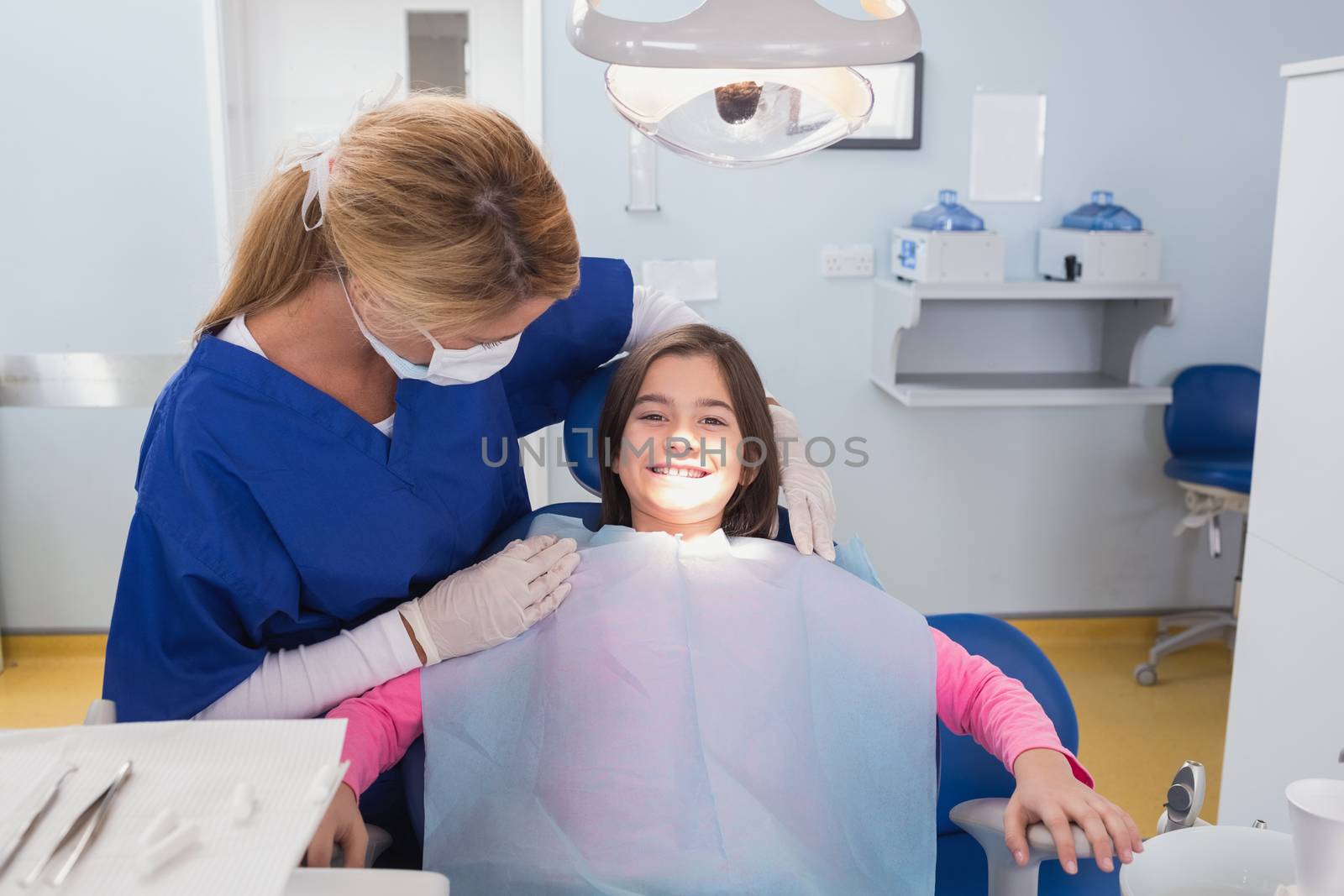 Pediatric dentist examining her smiling young patient in dental clinic