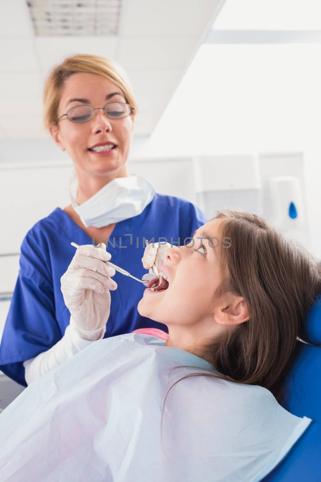 Smiling pediatric dentist examining her young patient by Wavebreakmedia