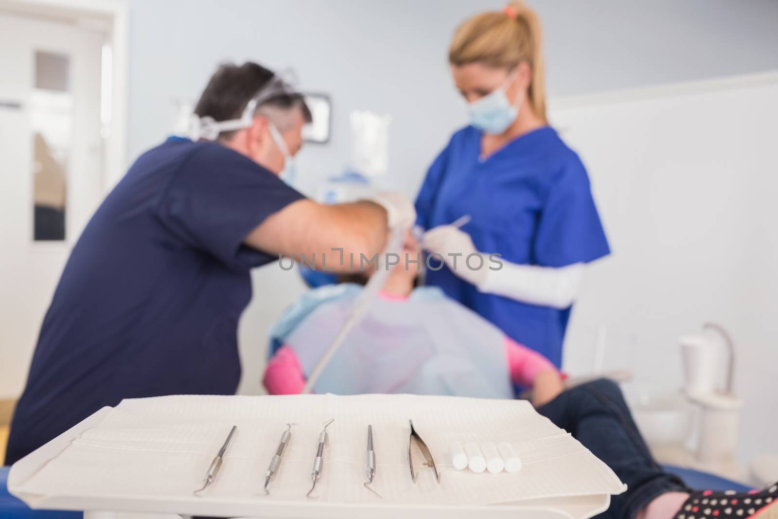 Dentist and his dental assistant examining a young patient in dental clinic
