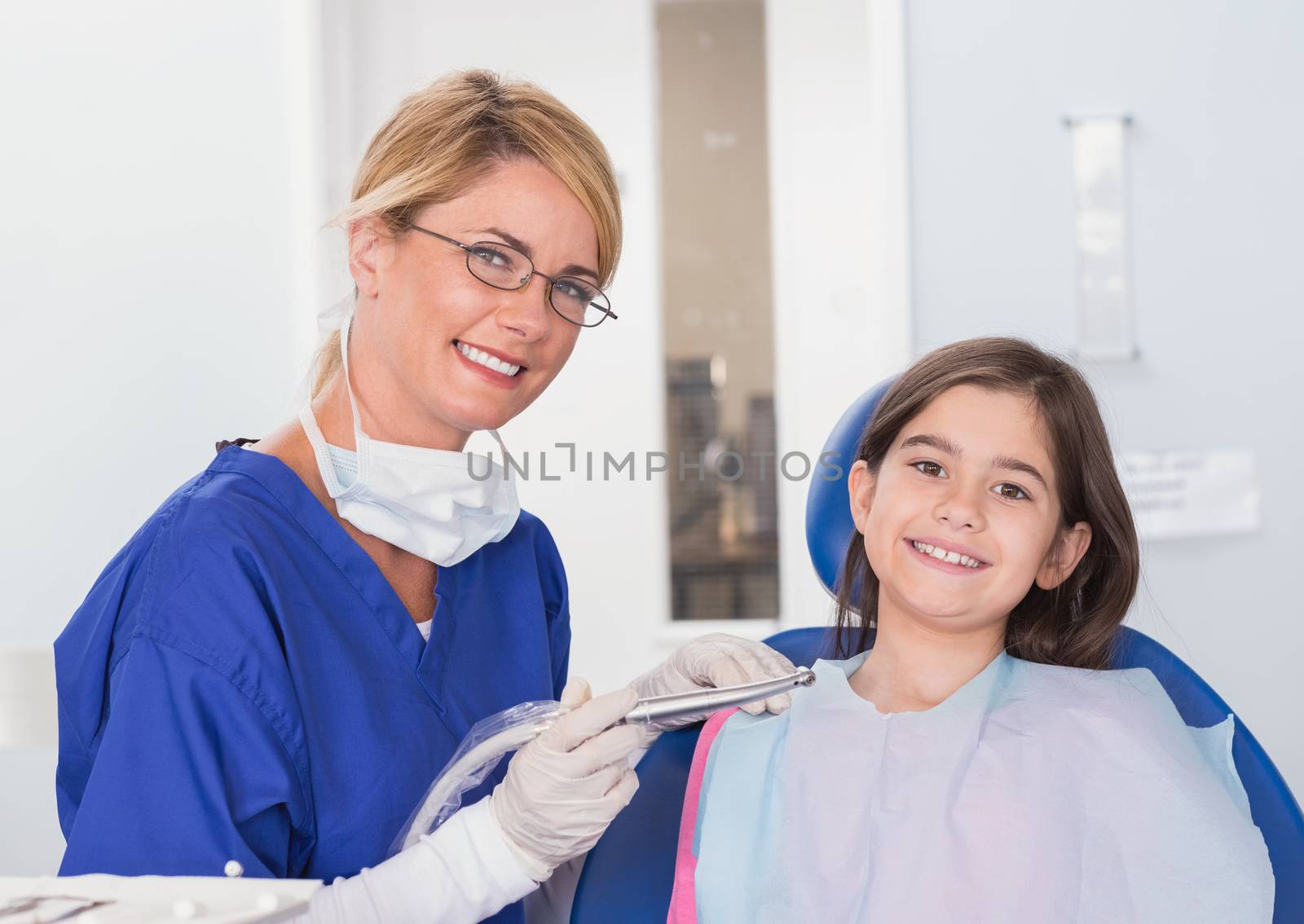 Portrait of a smiling pediatric dentist and young patient in dental clinic