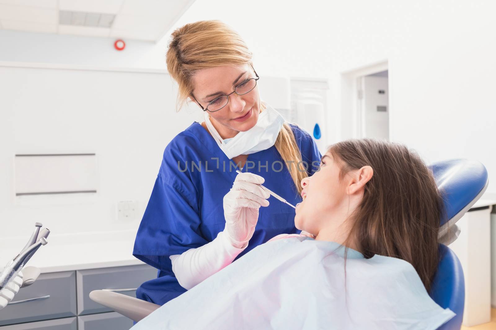 Pediatric dentist examining her young patient in dental clinic