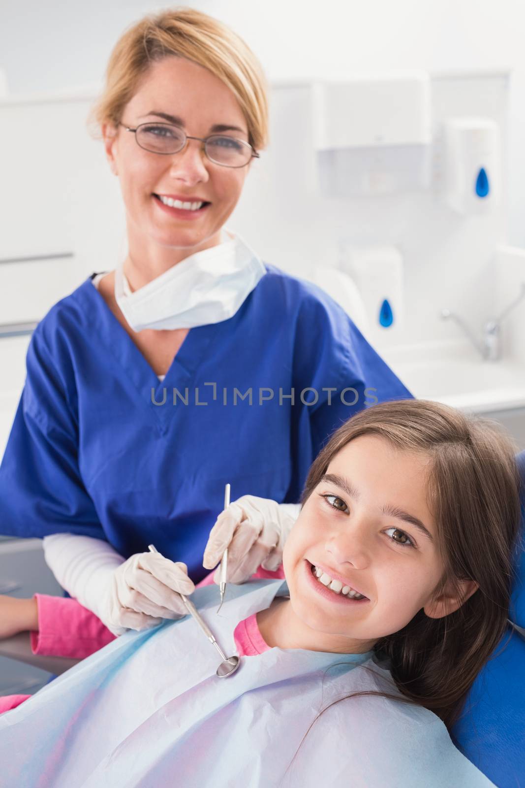 Smiling pediatric dentist with a happy young patient  by Wavebreakmedia
