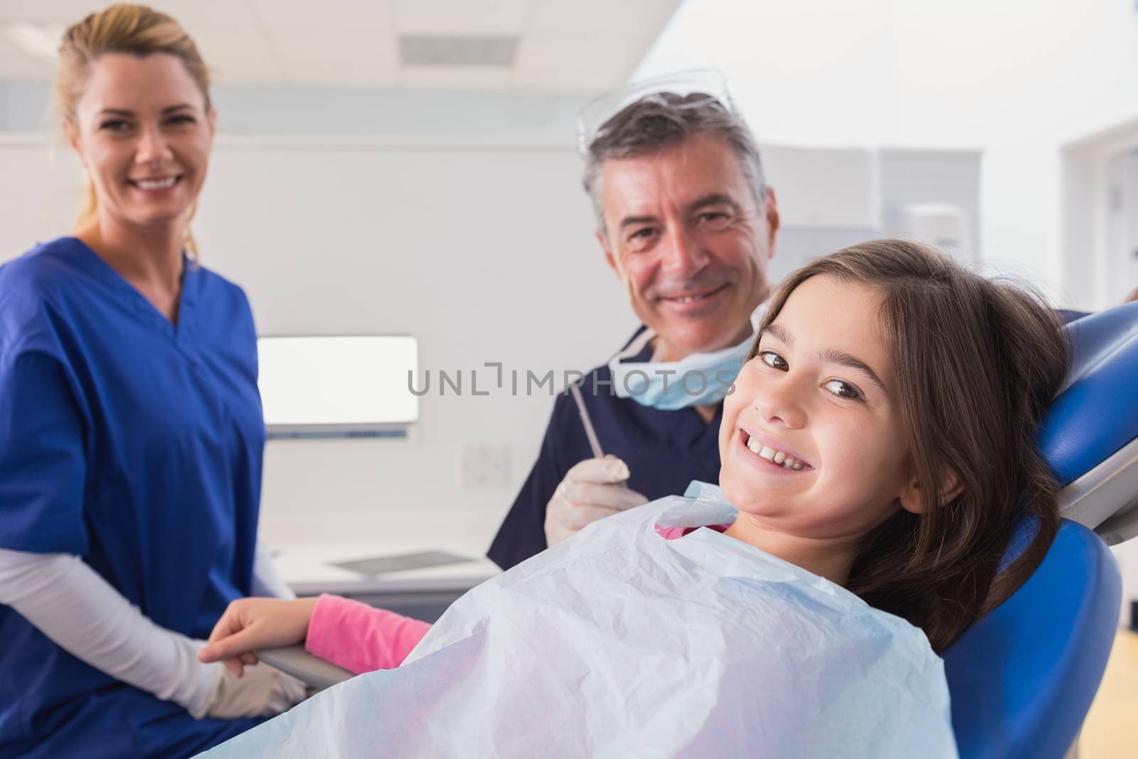 Smiling pediatric dentist and nurse with a young patient in dental clinic