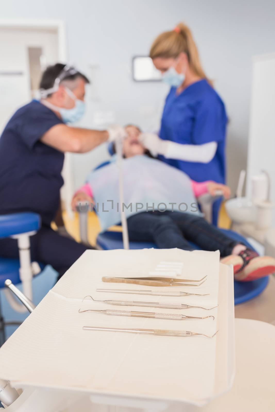 Dentist and his dental assistant examining a young patient in dental clinic