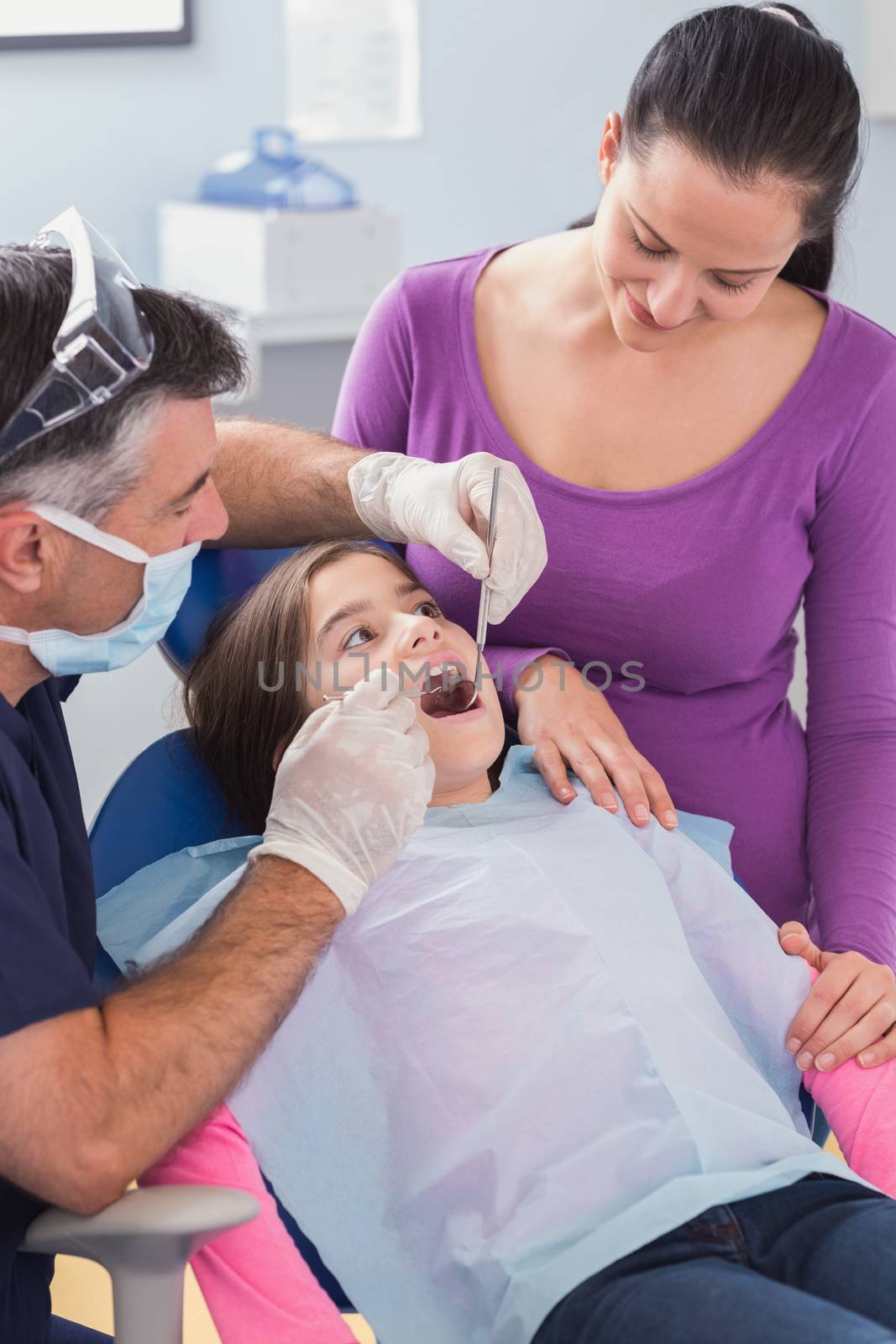 Pediatric dentist examining young patient with her mother by Wavebreakmedia