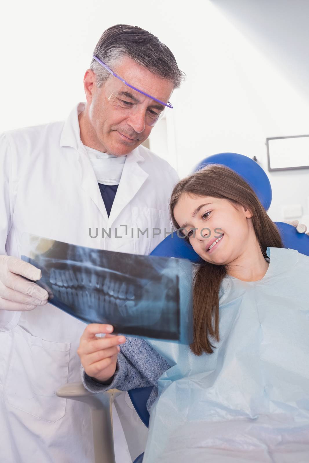 Pediatric dentist explaining to young patient the x-ray in dental clinic