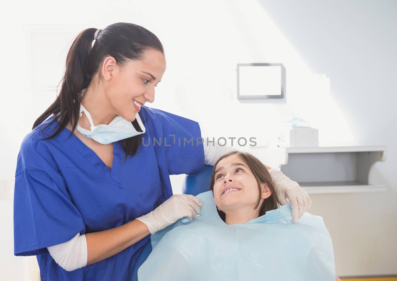Pediatric dentist putting on her young patient the scrubs in dental clinic