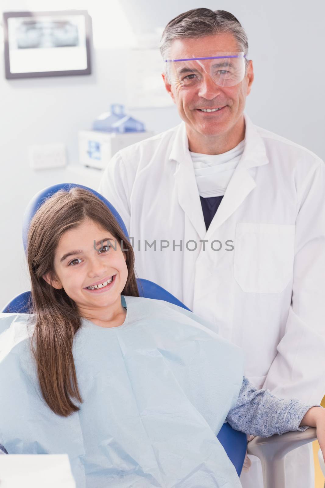 Smiling dentist with safety glasses and happy young patient in dental clinic