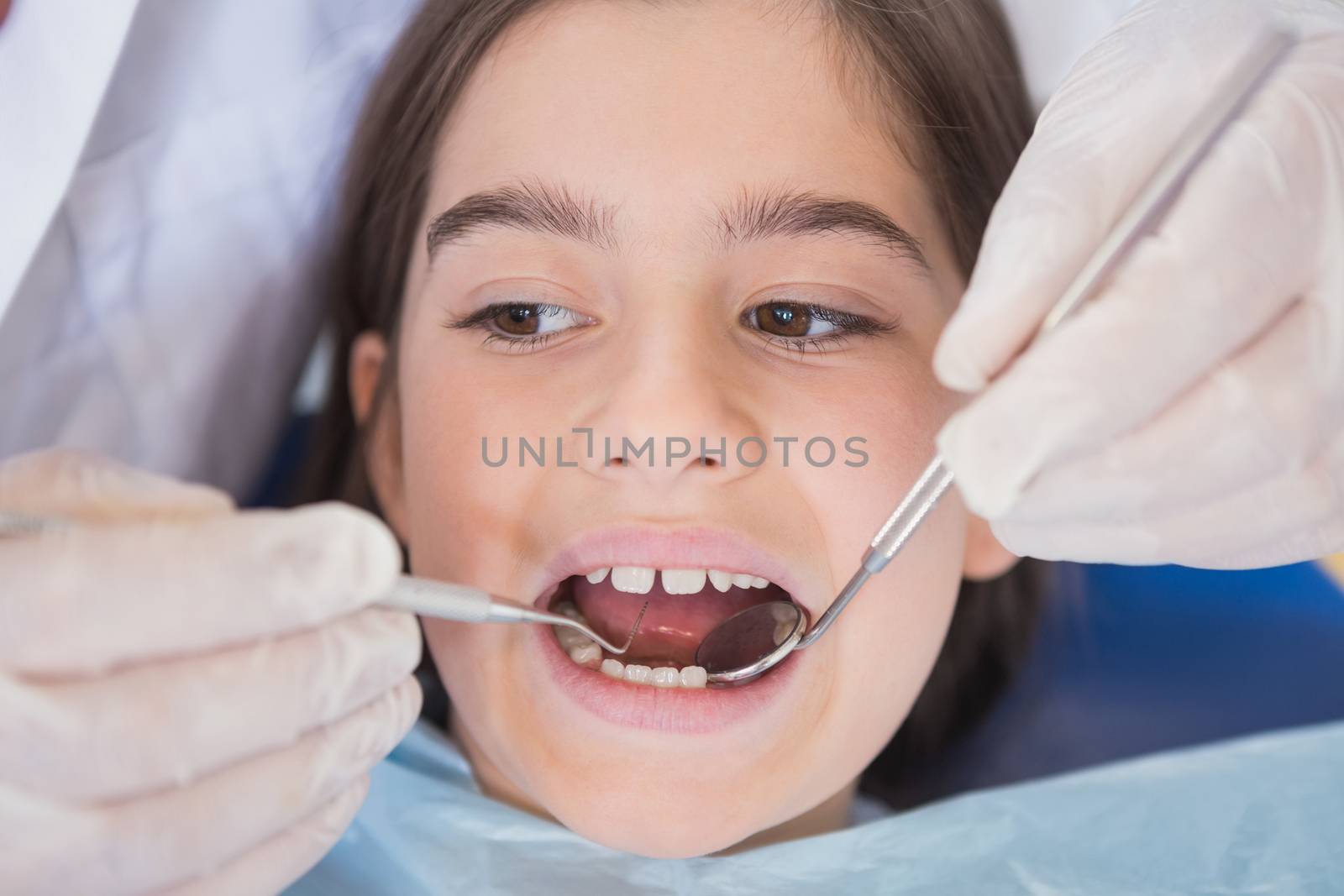 Dentist using dental explorer and angled mirror in mouth open of a patient 