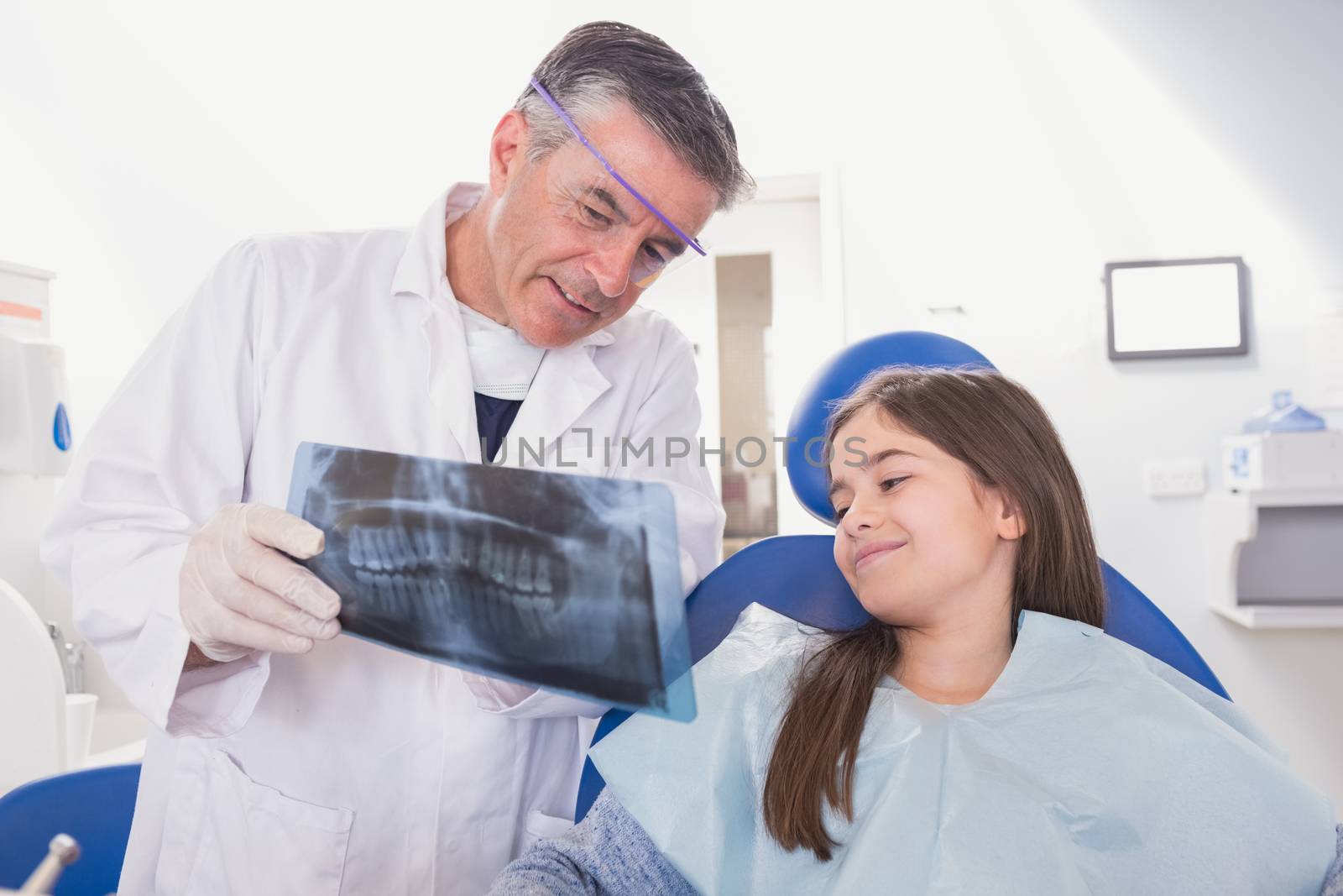 Pediatric dentist explaining to young patient the x-ray in dental clinic