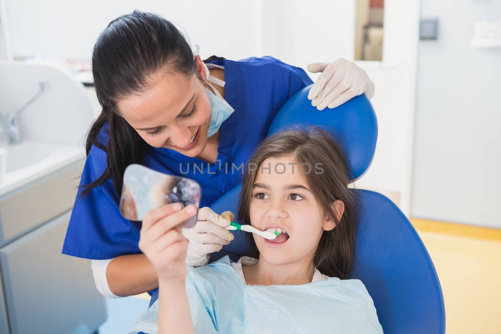 Pediatric dentist brushing teeth to her young patient  by Wavebreakmedia