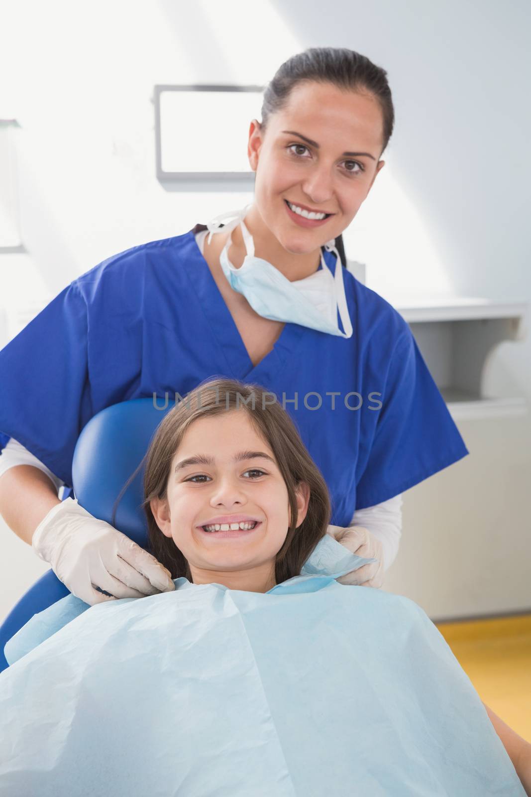Pediatric dentist putting on her young patient the scrubs by Wavebreakmedia