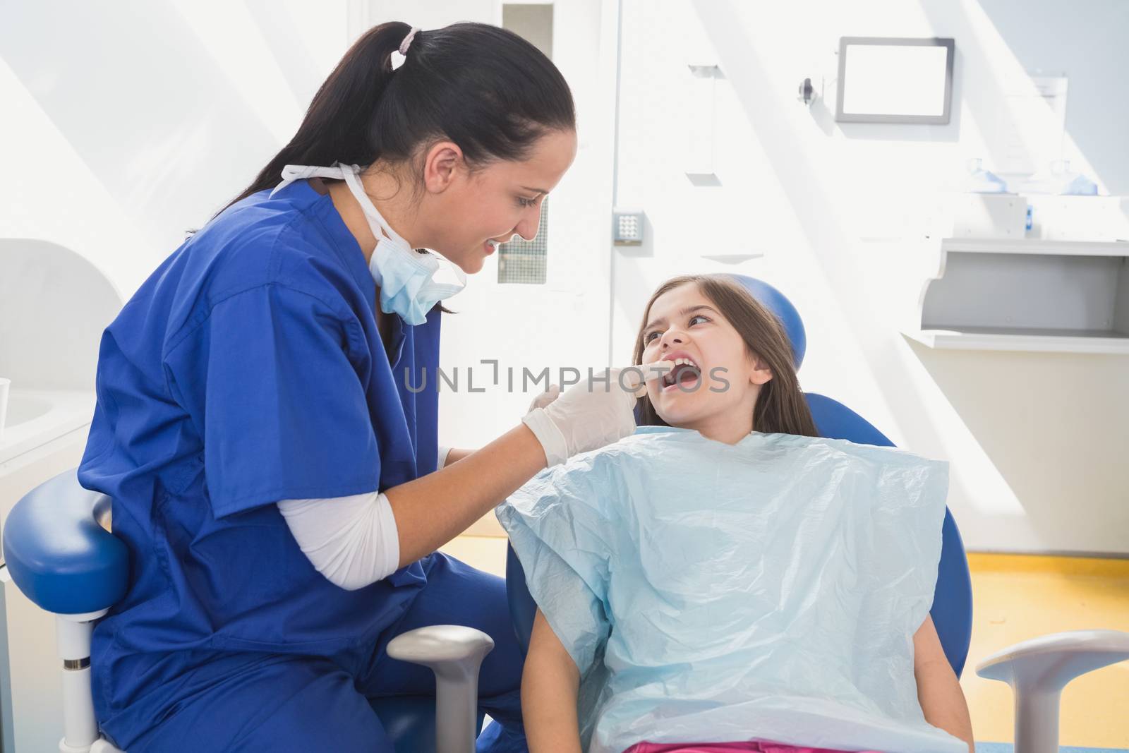 Pediatric dentist examining her young patient in dental clinic