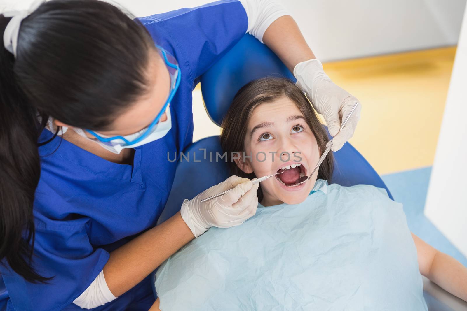Pediatric dentist examining her patient with mouth open in dental clinic
