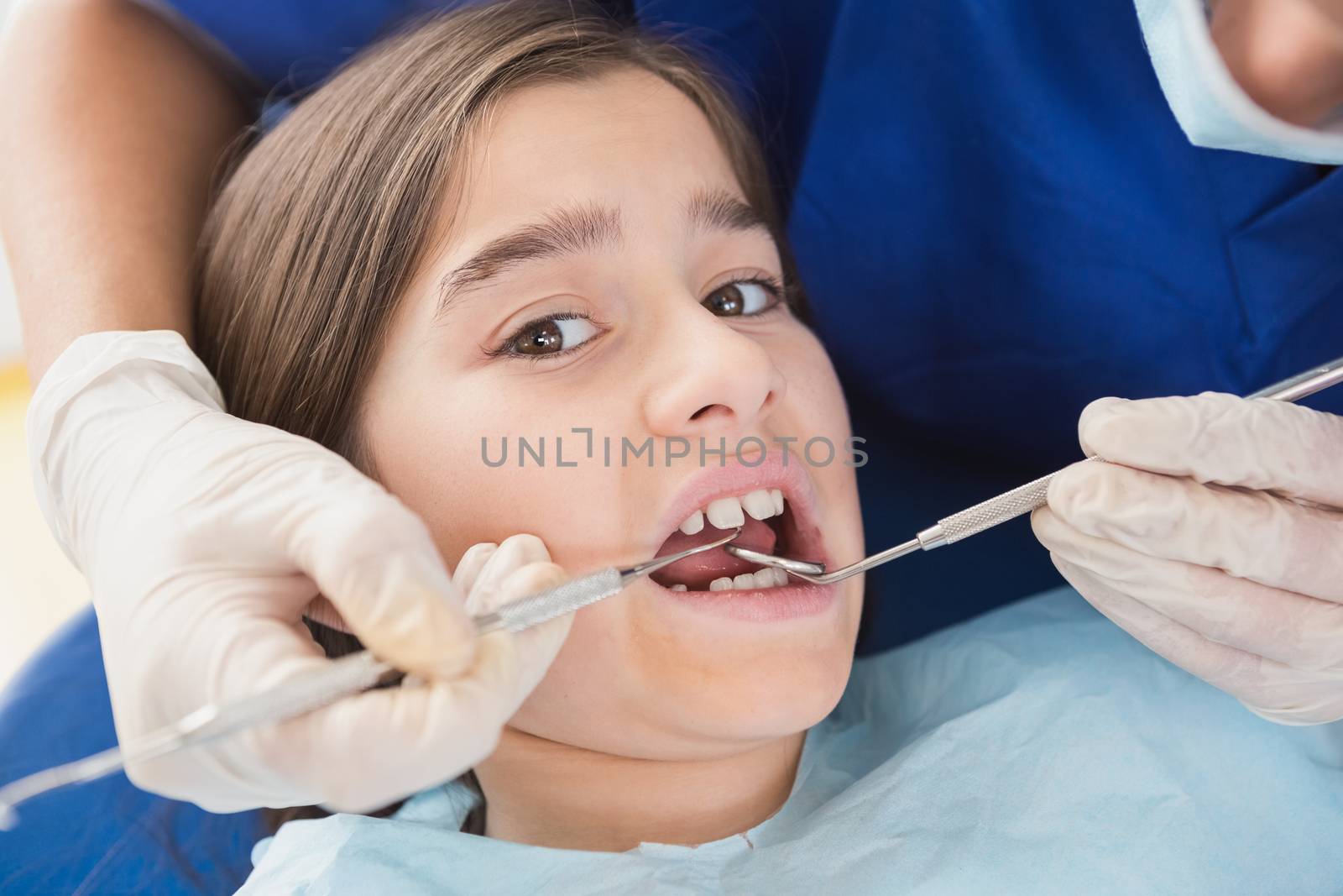 Pediatric dentist using dental explorer and angled mirror in mouth open of a patient 