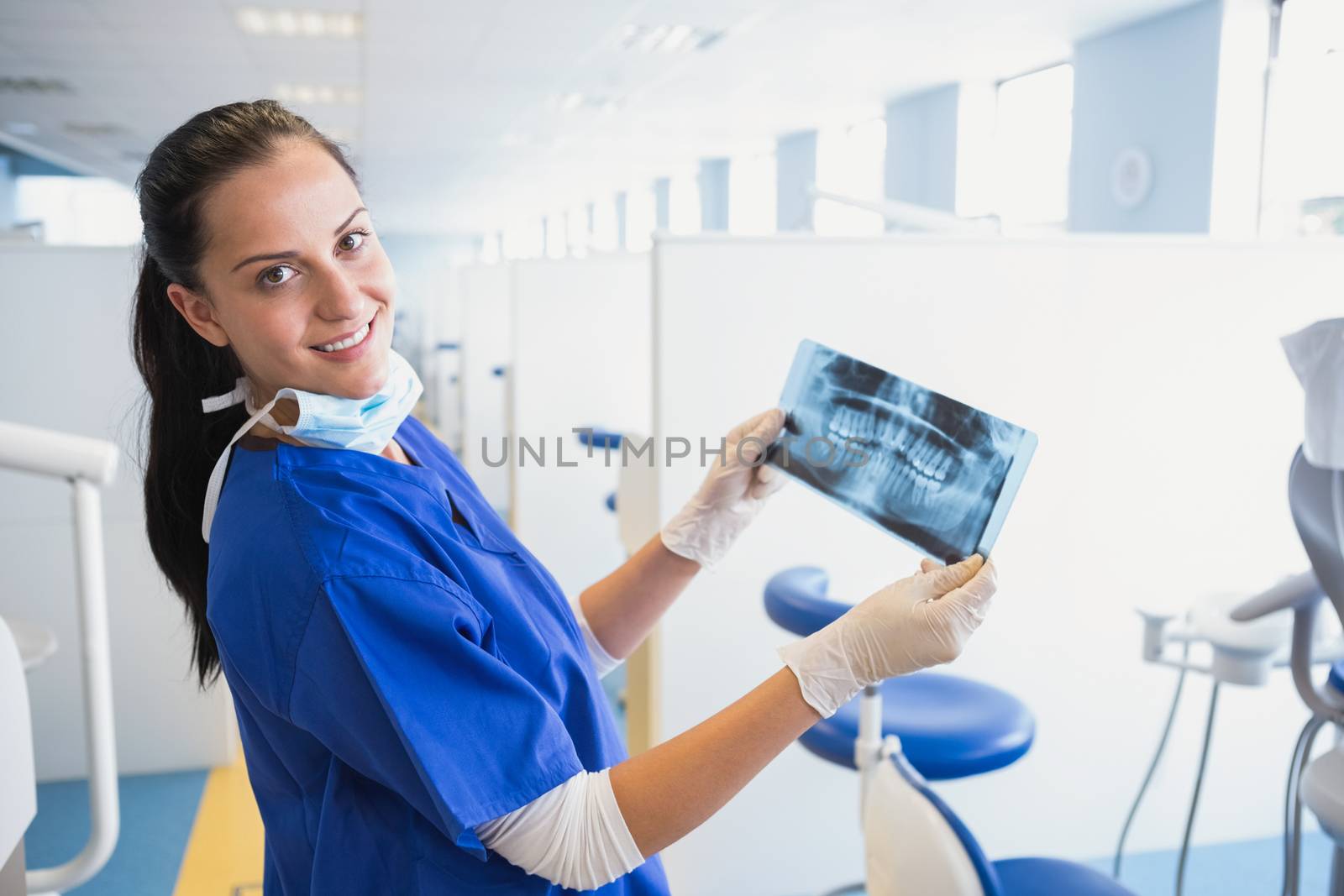 Smiling dentist examining a x-ray  by Wavebreakmedia