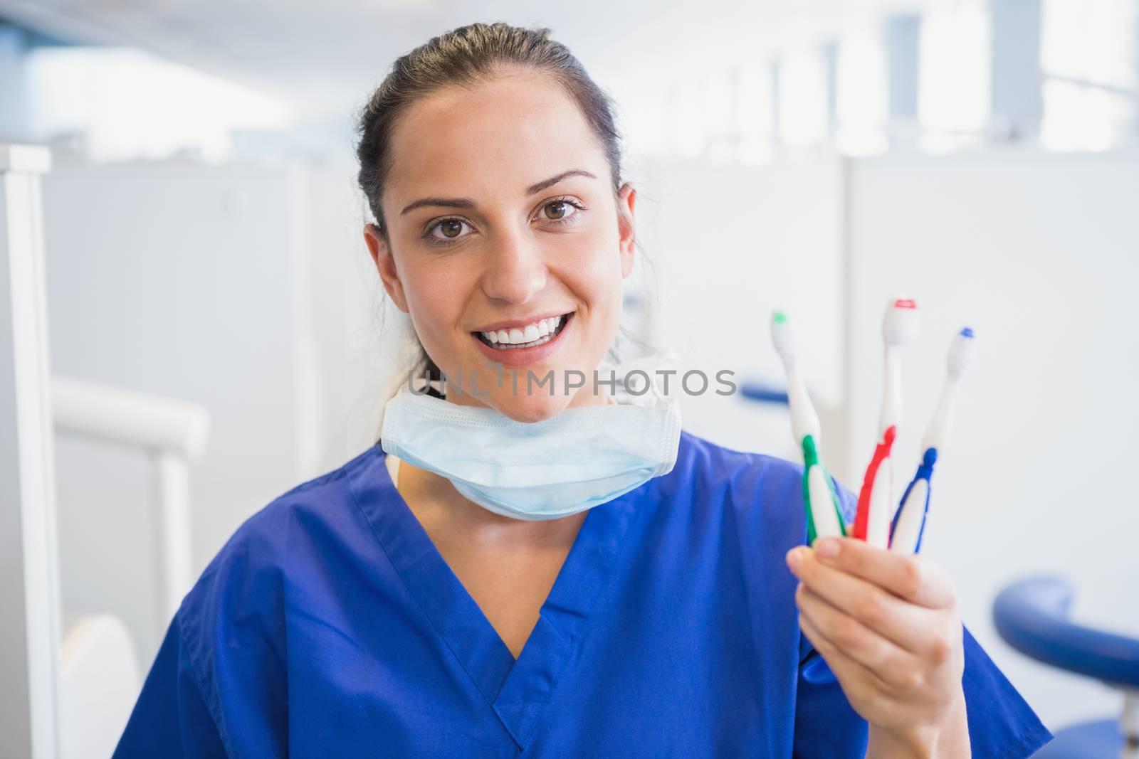 Portrait of a smiling dentist showing toothbrush in dental clinic