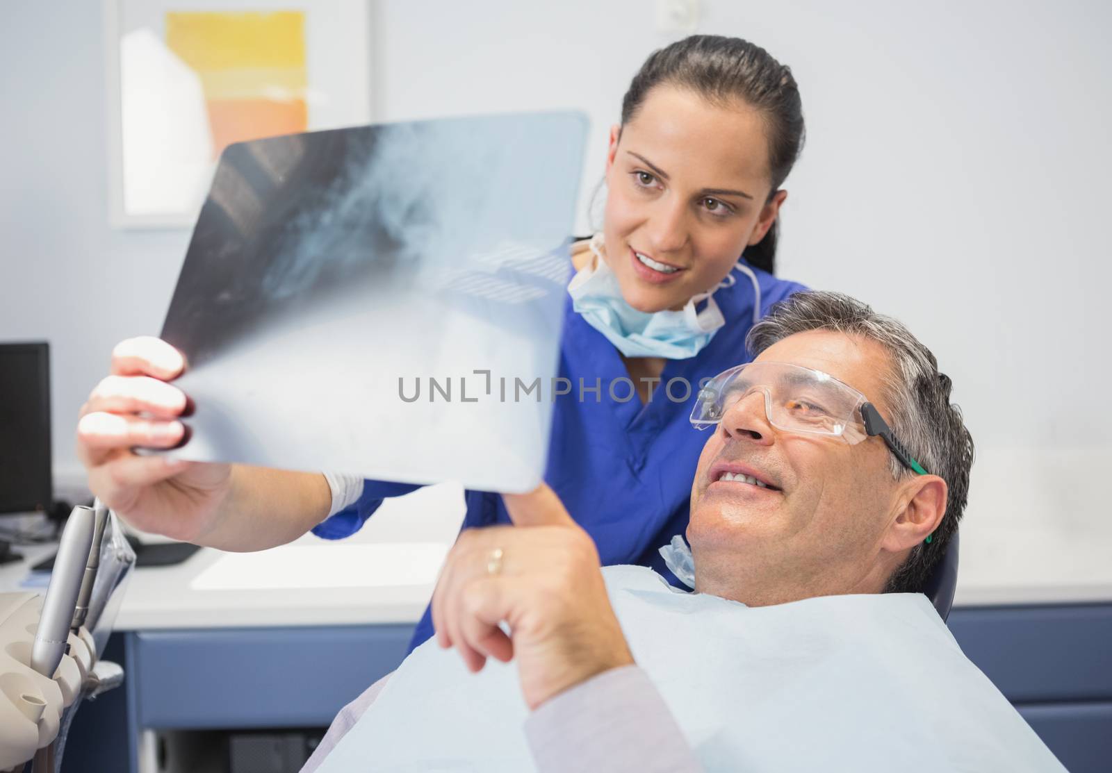 Smiling dentist showing x-ray to her patient  by Wavebreakmedia
