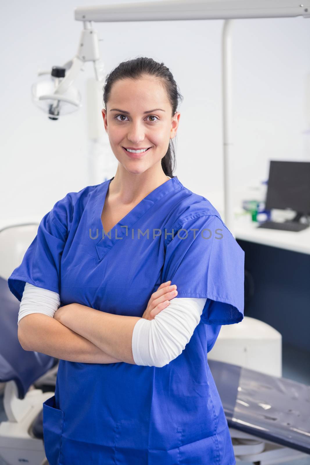 Smiling dentist with arms folded in dental clinic