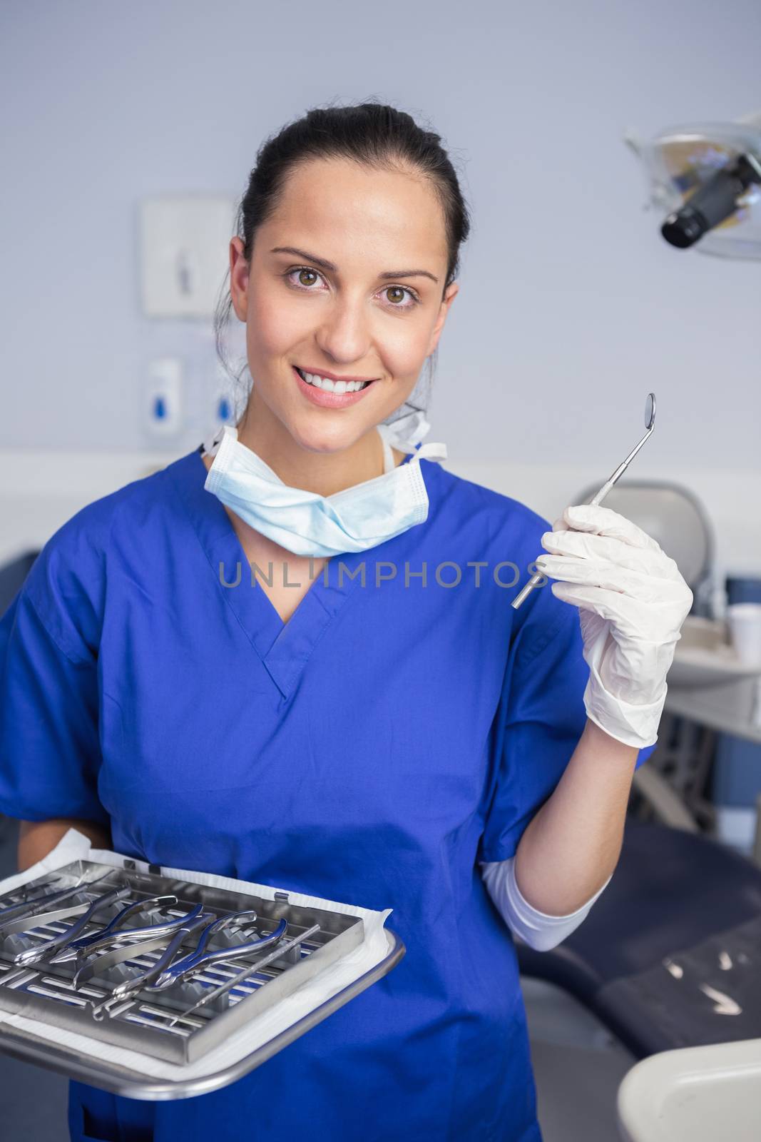 Smiling dentist holding tray and angle mirror  by Wavebreakmedia