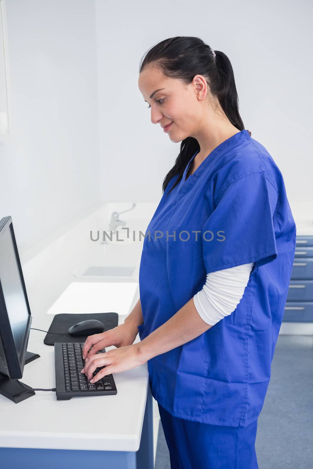 Smiling dentist typing on keyboard in dental clinic