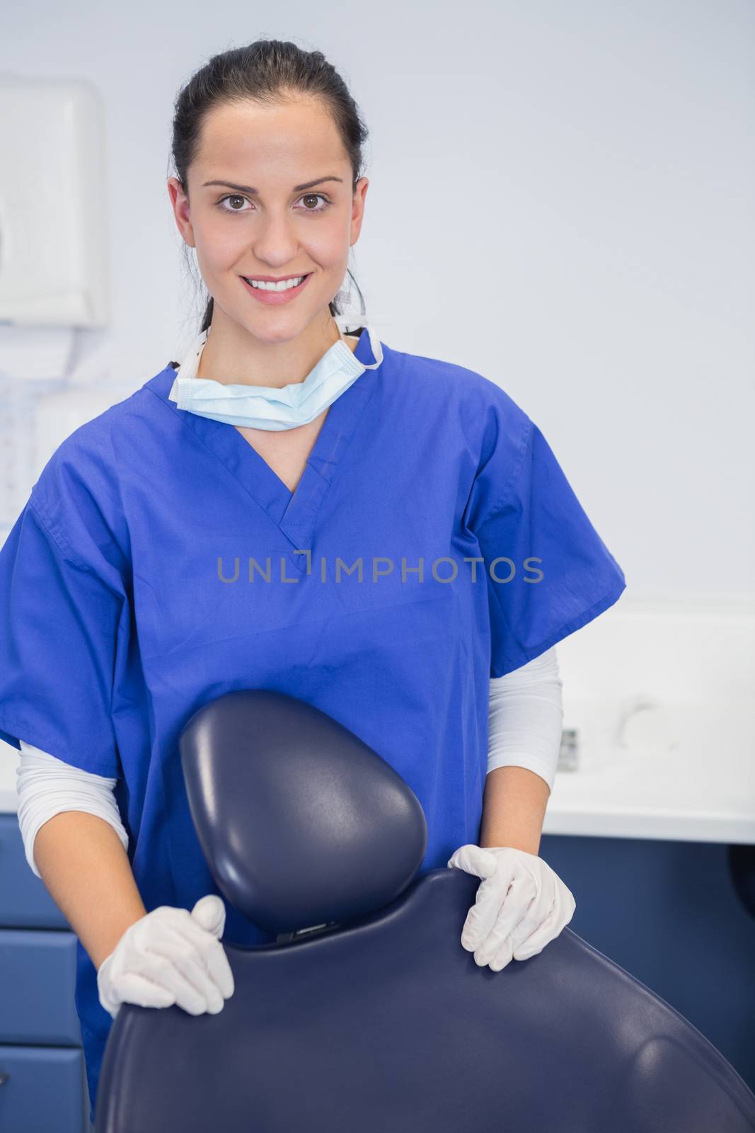 Portrait of a cheerful dentist behind a dentists chair in dental clinic