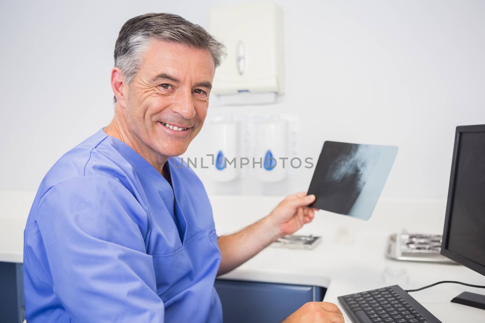 Portrait of a smiling dentist holding x-ray in dental clinic