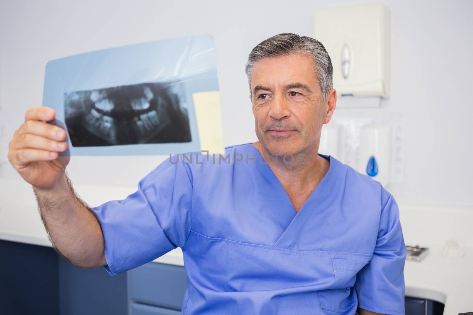 Thoughtful dentist studying x-ray attentively in dental clinic