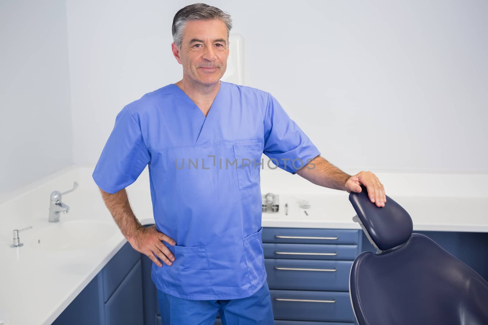 Portrait of a friendly dentist near dentists chair in dental clinic