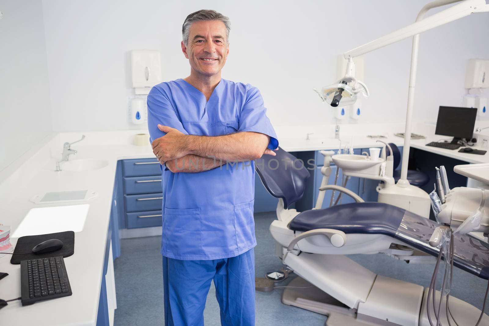 Happy dentist standing with arms crossed by Wavebreakmedia